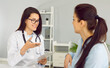 © Studio Romantic - Smiling friendly female doctor discusses diagnosis with woman and makes notes in clipboard. Female patient at reception in medical clinic. High level medical services concept. Focus on doctor.