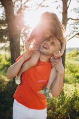 Wall Mural - little girl is sitting on her father's shoulders in the summer in the park