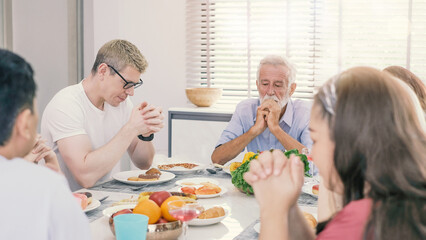 Multiethnic family praying at the table worshipping the Lord. praying before lunch, thanking God for meal, religion. family saying grace. thanksgiving..