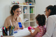© cherryandbees - psychologist talks to young girl in kindergarden. speech support session