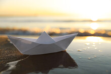 White Paper Boat On Wet Sand Near Sea At Sunset, Space For Text