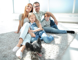 Wall Mural - portrait of a happy family sitting on the living room floor