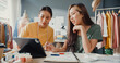 © tirachard - Two professional Asia cheerful lady fashion designer teamwork with casual site on table use tablet meeting discuss final design share idea in shop. Lady tailor partner start up business cloth shop.