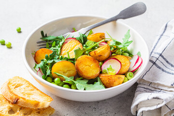 Wall Mural - Summer potato and pea salad with arugula and radish in white bowl. Vegan recipe.