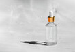 Transparent glass dropper bottle with golden cap on gray background. Pipette with fluid hyaluronic acid, serum, retinol or oil. Cosmetics and healthcare concept. Flat lay. Luxury beauty product