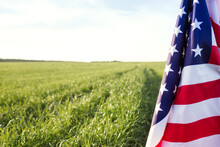 American Flag And Green Field. US Independence Day Or Memorial Day. Patriotic Background With Copy Space
