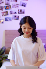Wall Mural - Smiling girl in white cotton t-shirt programming on laptop at home