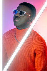 Wall Mural - Neon fashion. Cyberpunk style. Success confidence. Handsome cool stylish serious man in trendy sunglasses in colorful bright glowing night light.