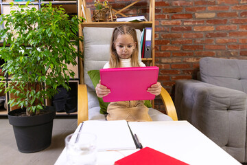 One beautiful little girl, school age kid studying at home using tablet. Model wearing eyeglasses. Education, childhood, people, homework and school concept.