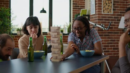 Wall Mural - Competitive person enjoying society game play with friends at board games gathering, having fun with wooden square tower and building blocks. Cheerful friends playing toy competition.