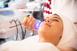 Asian woman getting lifting anti-aging, face massage and skincare by electroporation facial therapy aesthetic cosmetology