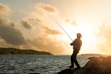 Bank Fishing. Fisherman With Spinning Rod At Sunset. Copy Space