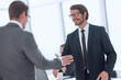 © ASDF - smiling business people holding out their hands for a handshake