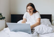 © mdyn - Portrait of beautiful young redhead woman with laptop on bed on a lazy day. Online education, working or shopping. Technology woman concept for alternative office freelance