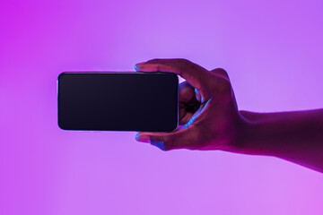 Poster - Closeup of young black guy holding smartphone with empty screen, showing space for mobile app or website in neon light