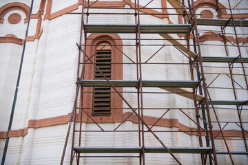 Closeup of scaffolding on the side of a orthodox church, under restoration, rebuilding. Restoring old monastery. Scaffolding construction. Repair of the facade on historic building.