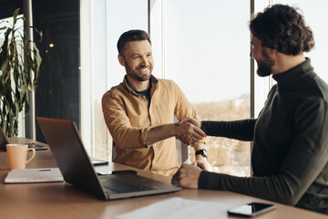 Poster - Successful businessmen shaking hands in agreement, sitting at desk with laptop at company office, free space
