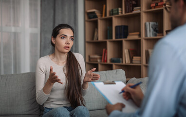 Wall Mural - Unhappy sad emotional european millennial woman client talking to psychologist guy in clinic