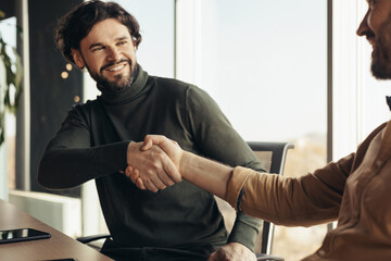 Canvas Print - Happy businessmen handshaking after successful agreement at contemporary office, selective focus. Business partnership