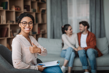 Wall Mural - Happy black woman psychologist in glasses show thumb up, smiling millennial european man looking at wife