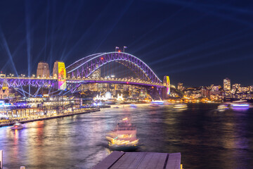 Wall Mural - Colourful Light show at night on Sydney Harbour NSW Australia. The bridge illuminated with lasers and neon coloured lights 