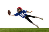 Fototapeta Sport - Dynamic portrait of little boy, beginner player of american football training isolated on white background with green grass flooring. Concept of sport, movement, achievements.