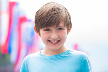 portrait of a smiling schoolboy against the background of white, red, blue flags outside