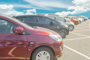 Wall Mural - Cars parking in asphalt parking lot in a row with blue sky background. Outdoor parking lot