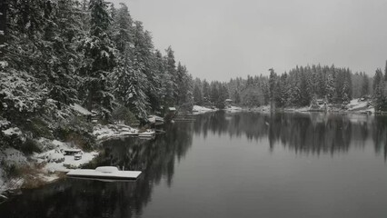 Wall Mural - Floating over a lake in winter with the snow falling and calm water.
