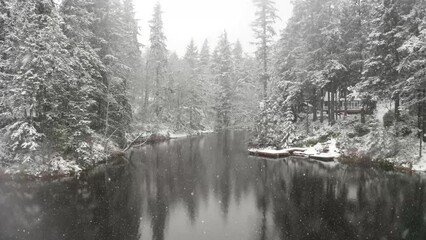 Wall Mural - Floating over a lake in winter with the snow falling and calm water.