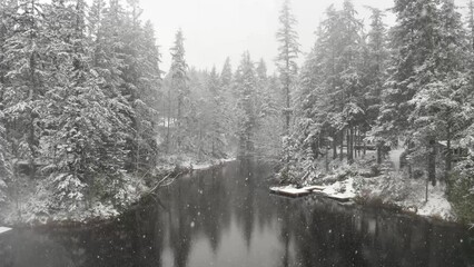 Wall Mural - Floating over a lake in winter with the snow falling and calm water.