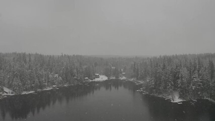 Wall Mural - Floating over a lake in winter with the snow falling and calm water.