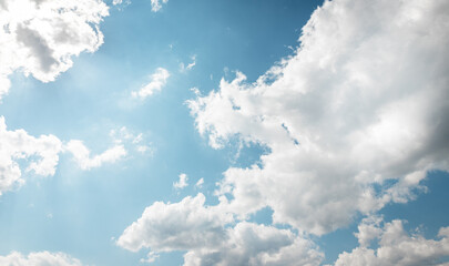 Wall Mural - Blue sky with sun behind white clouds background. Cloudy weather and sunlight. High quality photo