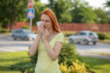  Young redhair woman sneezing in summer. Pollen Allergy symptoms