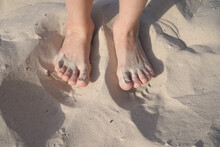 Two Bare Children's Feet Close-up On The Sand