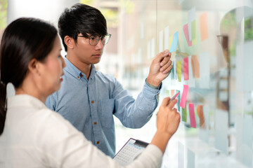 Poster - Two business executive team holding and taking notes keyword on board wall to brainstorm about a new business project for planning marketing plan together in the office