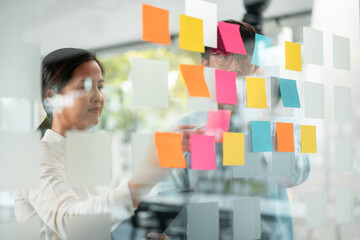 Poster - Two business executive team holding and taking notes keyword on board wall to brainstorm about a new business project for planning marketing plan together in the office