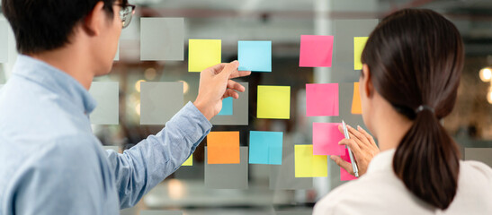 Poster - Two business executive team holding and taking notes keyword on board wall to brainstorm about a new business project for planning marketing plan together in the office