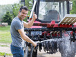 © Budimir Jevtic - Farmer washing tractor with equipment on farm