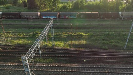 Poster - The view from the drone on the railroad tracks against the background of the setting sun. Concept of train traffic, rail transport, passengers. Aerial view of tracks, freight trains, train station.