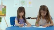 © Kiattisak - Woman teacher teaching little girl to paint color book on the table in classroom,kindergarten education school.Multi-ethnic preschool teacher and students in classroom.Kindergarten and study concept.