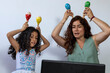 © Amilciar - Latin American mom and daughter giving virtual music lessons with percussion instruments
