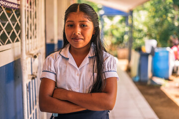 Nicaraguan elementary student girl smiling and looking at the camera with her arms crossed in a school in the rural area of Masaya