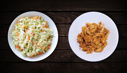 Wall Mural - Side dishes, sweet chicken cutlet dish and coleslaw are on white plate on dark wooden background, top view.