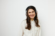 © Tatiana - portrait of a beautiful happy woman with long dark hair happily listening to music with headphones on a light monochrome background for inserting an advertising layout