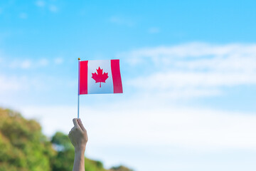 hand holding Canada flag on blue sky background. Canada Day  and happy celebration concepts