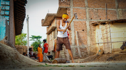 indian man splitting wood and cutting firewood with axe