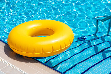 Wall Mural - Yellow ring floating in blue swimming pool. Inflatable ring, rest concept