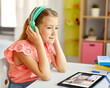 © Syda Productions - school, education and distance learning concept - little student girl in headphones with tablet computer having online class at home from top