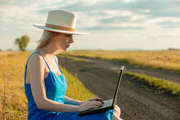 Sticker - Girl in blue dress with laptop computer sit on country road in summer.